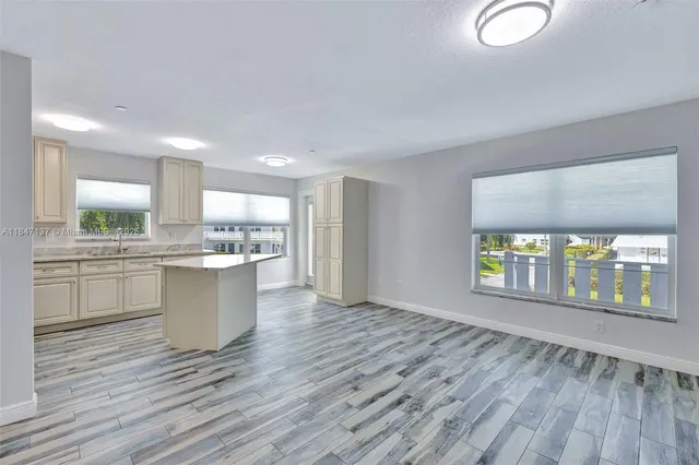 a large white kitchen with wooden floors and view living room