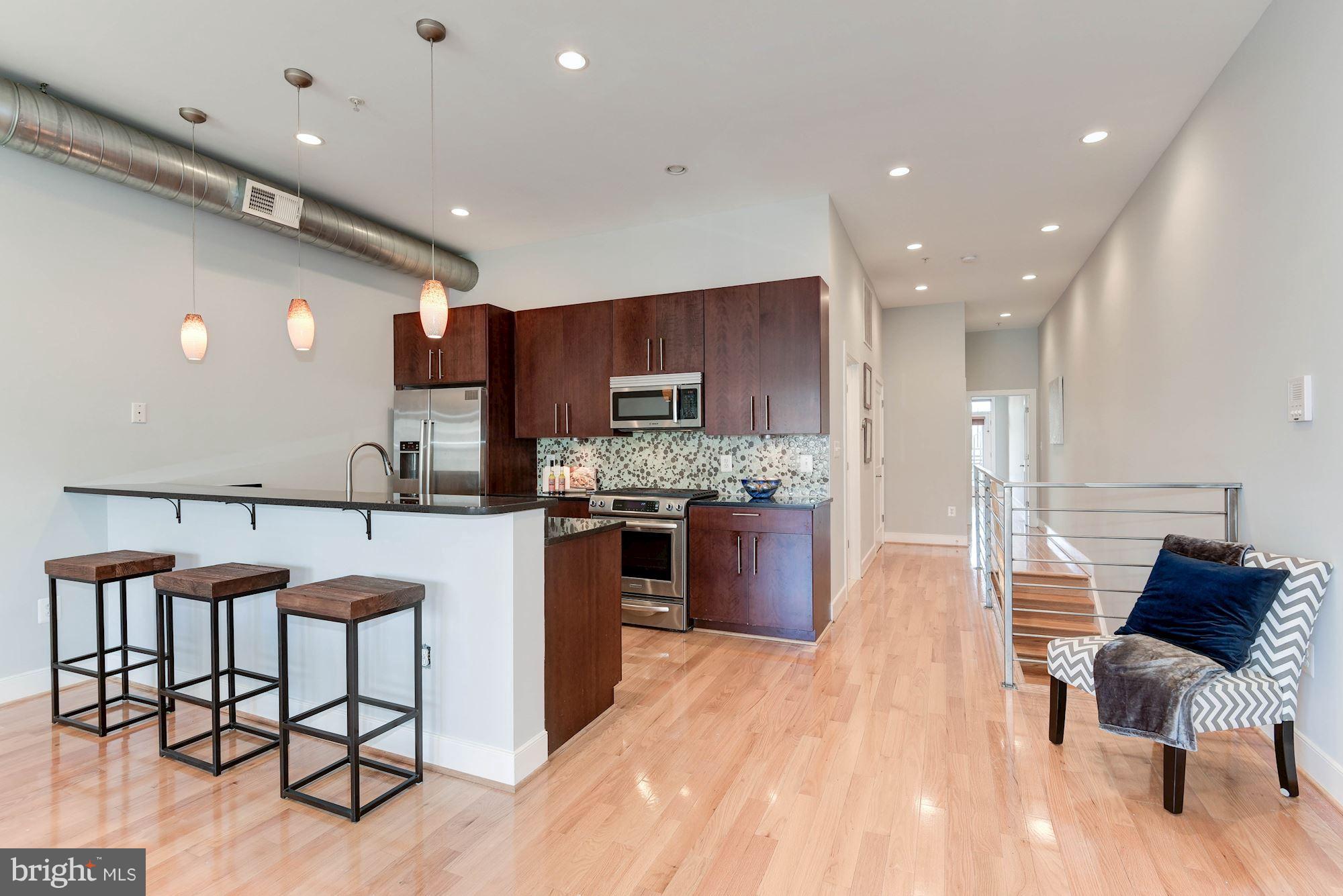 2444 Ontario Road Northwest, Unit 4 Washington, DC 20009 - Photo 11 of 26 a kitchen with stainless steel appliances granite countertop a refrigerator and a stove top oven with wooden floor