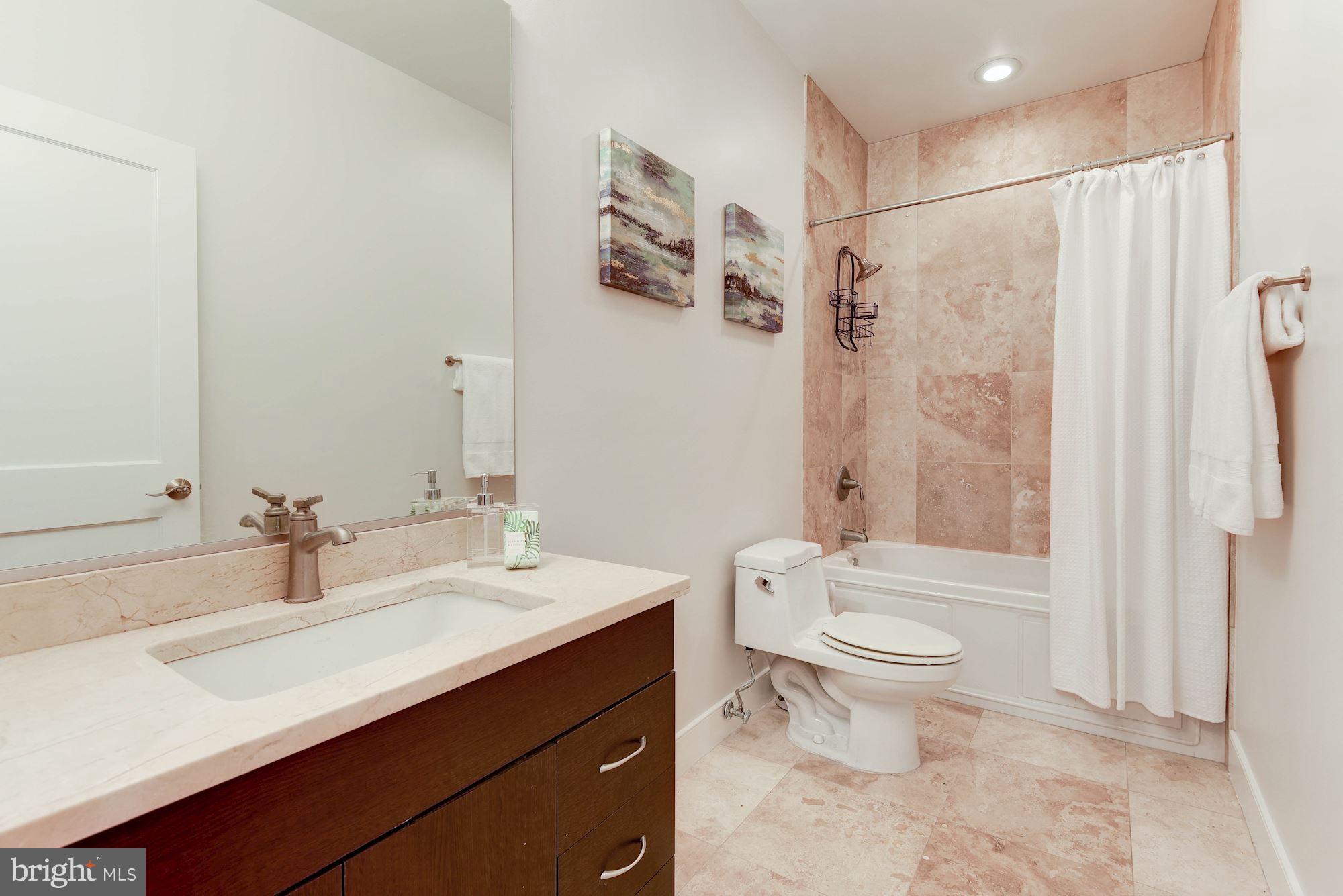 2444 Ontario Road Northwest, Unit 4 Washington, DC 20009 - Photo 21 of 26 a bathroom with a sink a toilet a mirror a vanity and shower