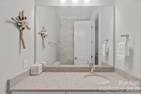 a bathroom with a granite countertop sink a mirror and shower