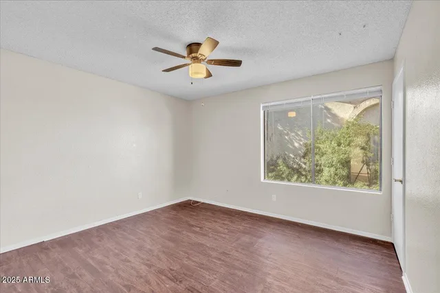 a view of an empty room with window and wooden floor