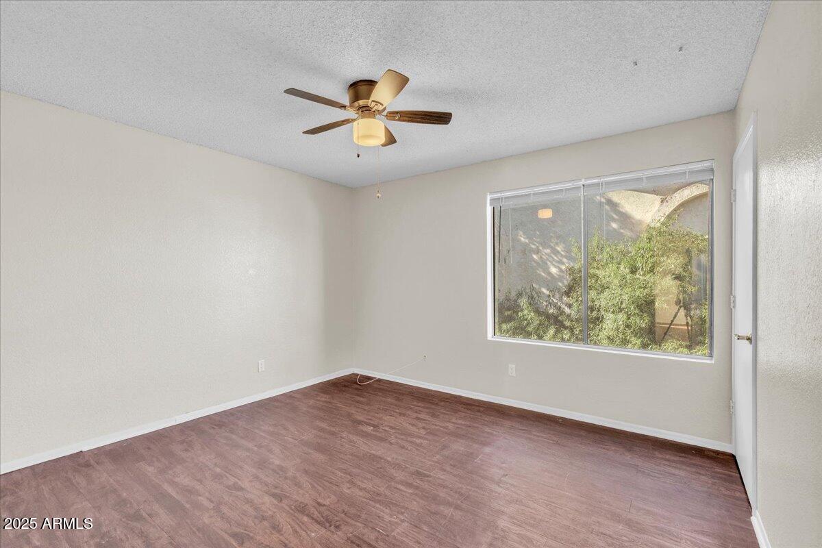 2437 East Tracy Lane, Unit 2 Phoenix, AZ 85032 - Photo 18 of 30 an empty room with wooden floor fan and windows