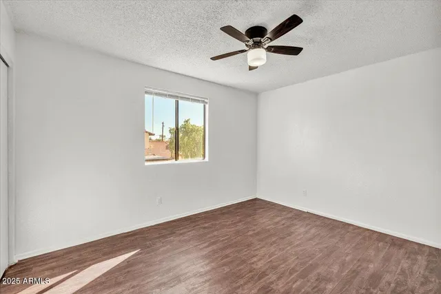 an empty room with wooden floor closet and ceiling fan window