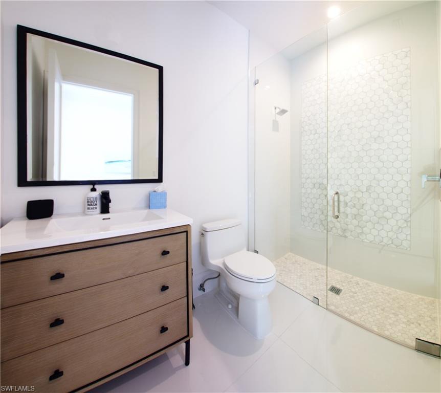 700 Wedge Drive Naples, FL 34103 - Photo 13 of 19 a bathroom with a toilet a sink a mirror and vanity