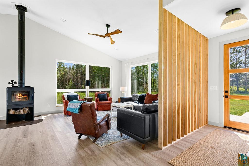 1873 East Shilhon Road Duluth, MN 55804 - Photo 8 of 26 Vaulted ceiling, wood-finish flooring, wood-burning stove, large windows, and a wood slat room divider