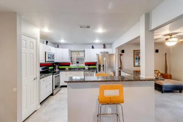 a kitchen with stainless steel appliances kitchen island granite countertop a stove and cabinets