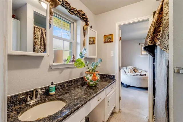 a bathroom with a granite countertop sink a large mirror and a window