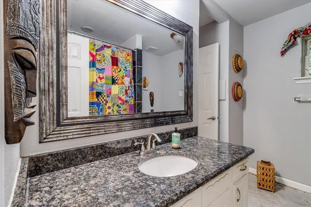a bathroom with a granite countertop sink and a mirror