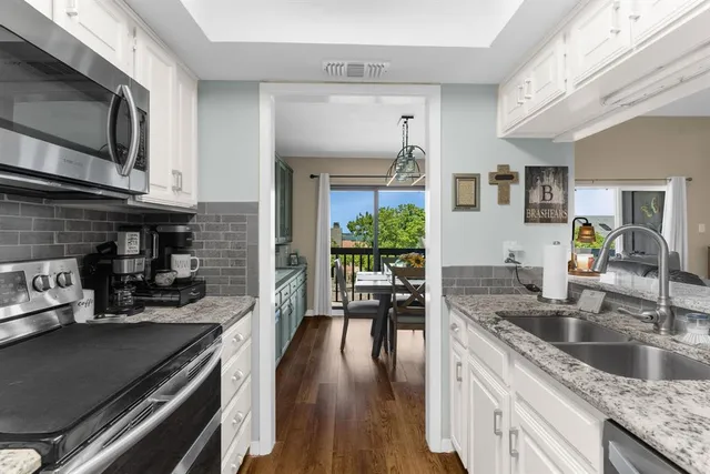 a kitchen with granite countertop a stove a sink and a wooden cabinets