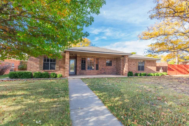 a view of a yard in front of a house with a large tree