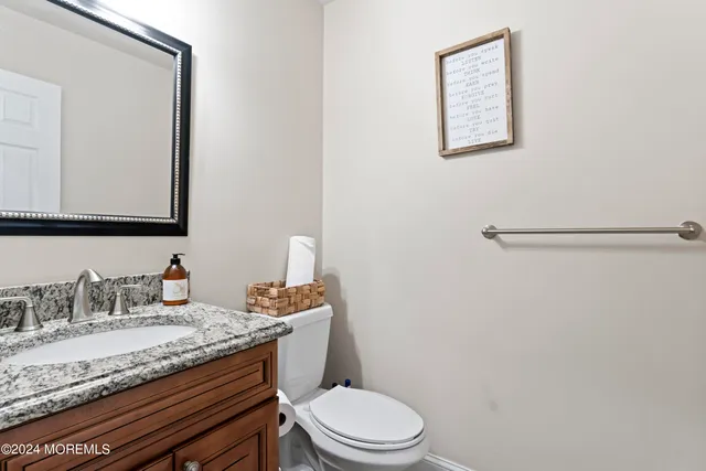 a bathroom with a granite countertop sink mirror vanity and toilet