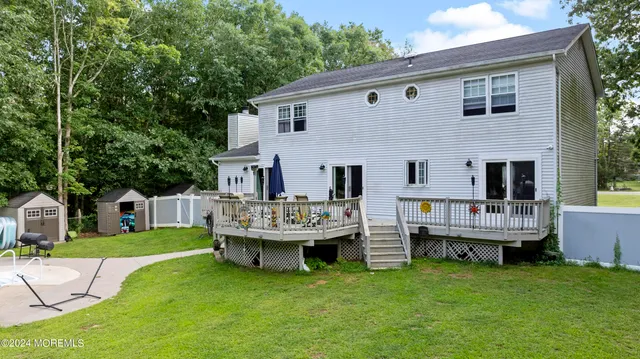 a view of house with a backyard and deck
