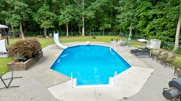 a view of a swimming pool with a patio and a backyard