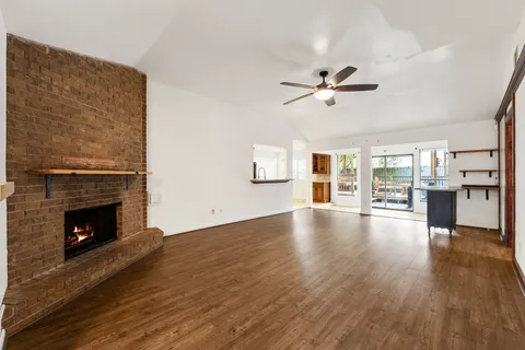 a view of an empty room with wooden floor and a fireplace