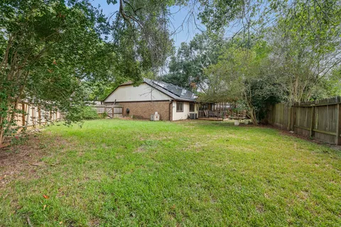 a backyard of a house with large trees and wooden fence