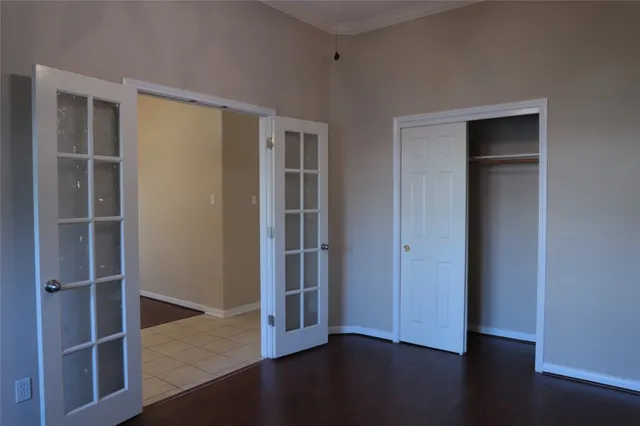 an empty room with wooden floor closet and windows