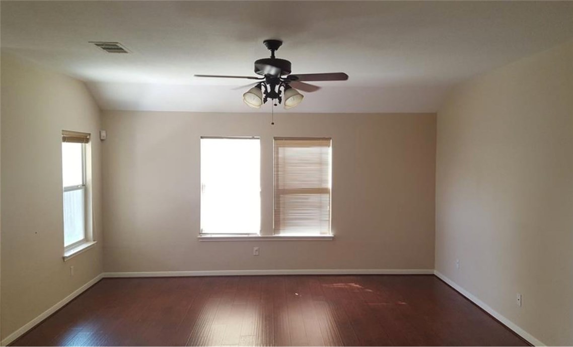 3936 Links Lane Round Rock, TX 78664 - Photo 15 of 40 an empty room with wooden floor chandelier fan and windows