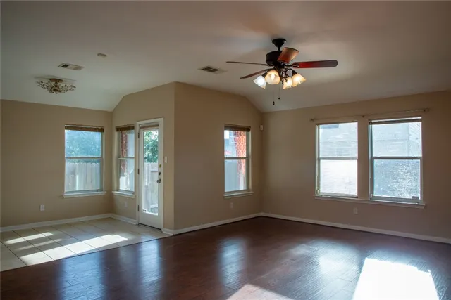 a view of an empty room with a window and wooden floor