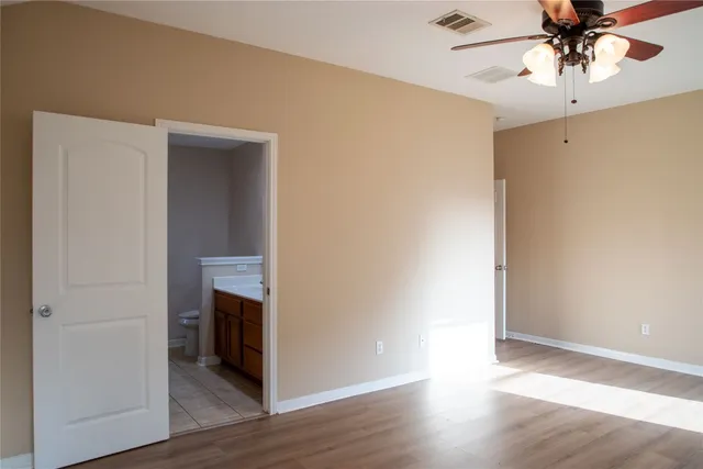 an empty room with wooden floor and chandelier fan