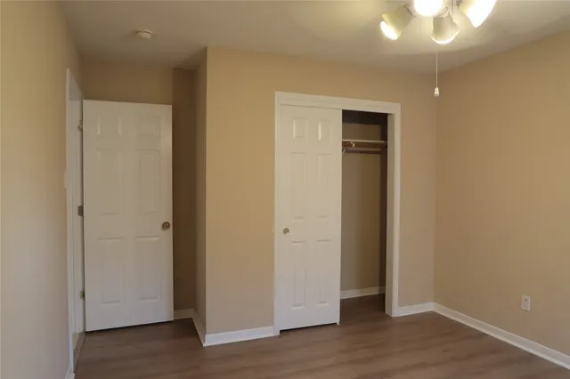 an empty room with wooden floor and closet area