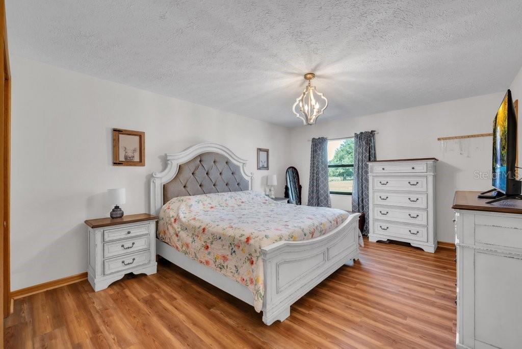5301 Coronet Road Plant City, FL 33566 - Photo 16 of 38 a bedroom with a bed and a chandelier