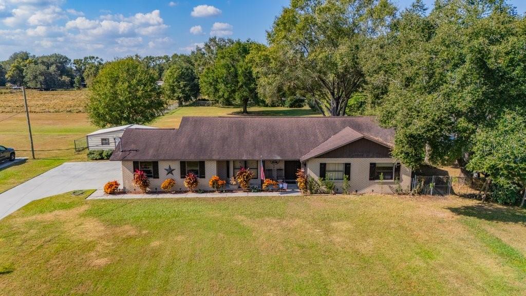 5301 Coronet Road Plant City, FL 33566 - Photo 3 of 38 a view of a white house with a big yard and potted plants