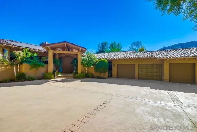 a front view of yellow house with a small yard and plants