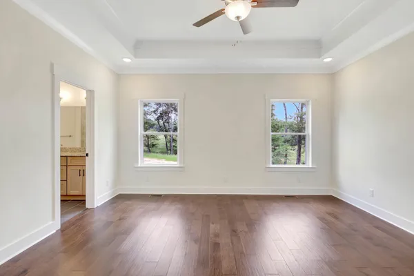 an empty room with wooden floor chandelier fan and windows