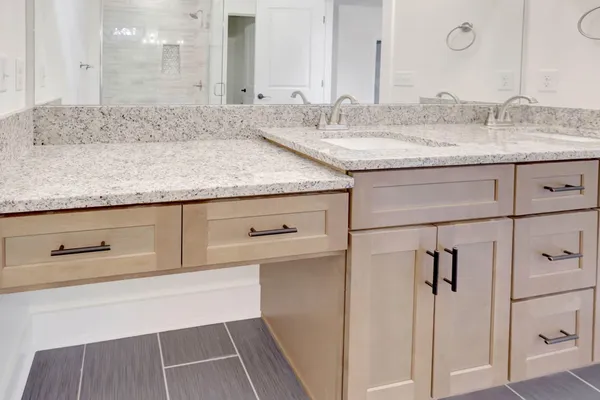 a bathroom with a granite countertop sink and white cabinets