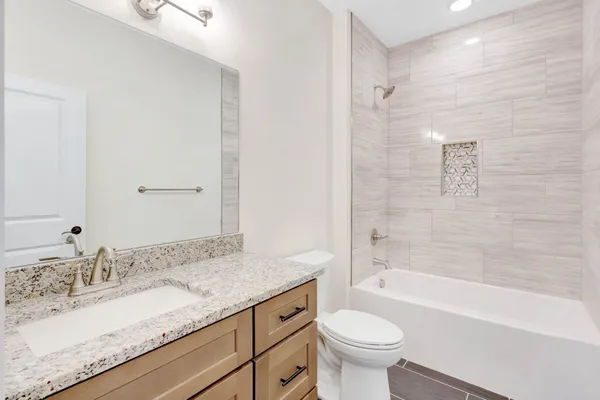 a bathroom with a granite countertop sink a toilet and a bathtub