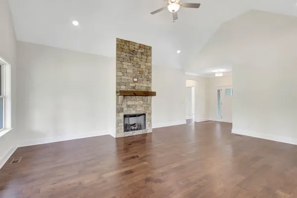 an empty room with wooden floor fireplace and windows