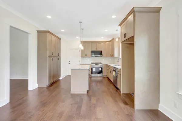 a view of kitchen with stainless steel appliances refrigerator oven and white cabinets with wooden floor