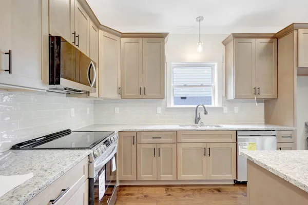 a kitchen with stainless steel appliances granite countertop a sink a stove and a microwave