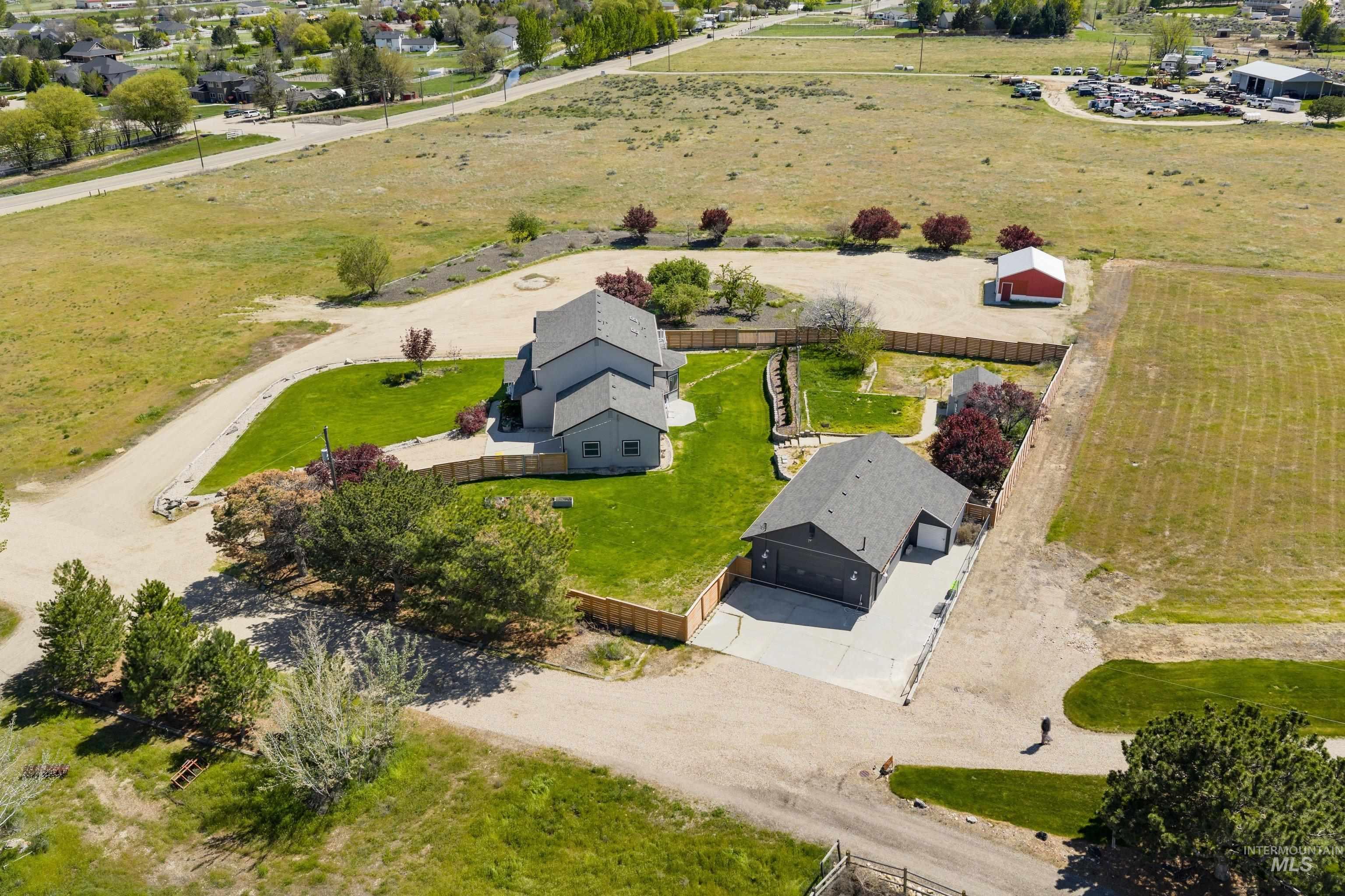 7657 Track Road Nampa, ID 83686 - Photo 45 of 49 Expansive property featuring a gray multi-story residence, a detached garage structure, a dedicated parking area, and a red outbuilding