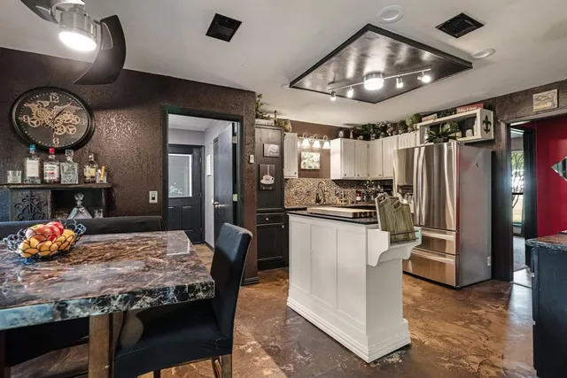 a kitchen with stainless steel appliances granite countertop a stove a refrigerator a microwave oven with a dining table and chairs