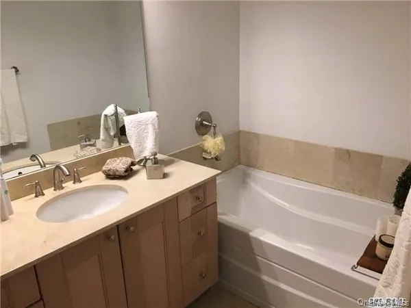 a bathroom with a sink vanity granite tub and a mirror