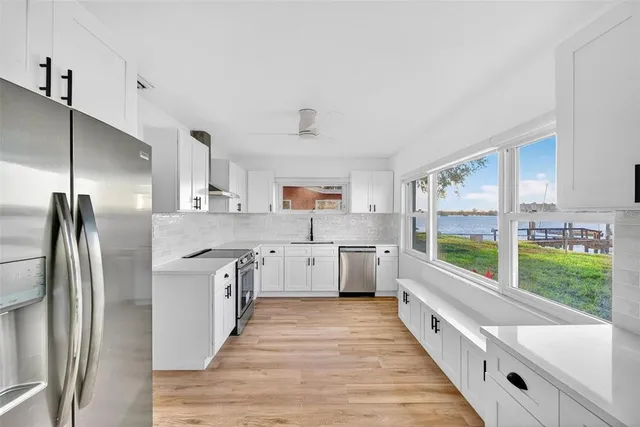 a large kitchen with stainless steel appliances a sink and a large window