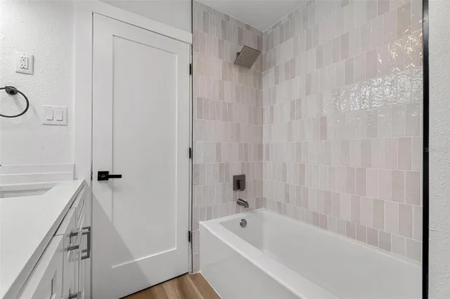 a bathroom with a tub shower vanity and a sink