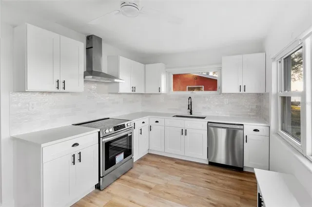 a kitchen with stainless steel appliances granite countertop a stove a sink and a white refrigerator with white cabinets