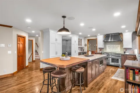 a large kitchen with granite countertop a stove a sink a dining table and chairs