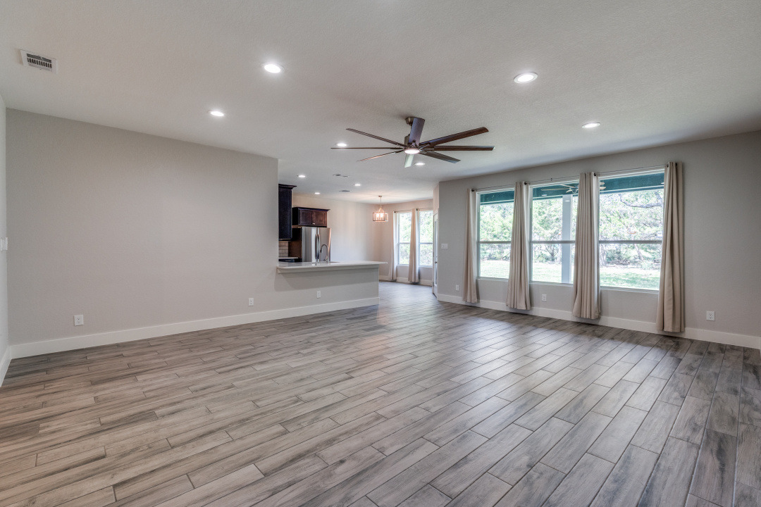 1848 Tanglewood Trail Spring Branch, TX 78070 - Photo 4 of 12 An open concept living area boasts wood-look tile flooring and views of the verdant backyard through large windows.