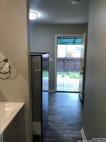 a view of a hallway with wooden floor and a bathroom
