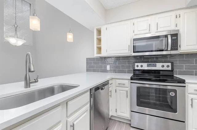 a kitchen with cabinets stainless steel appliances and a sink