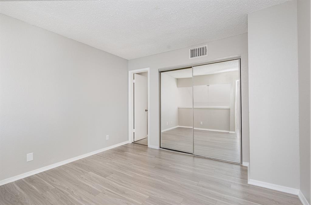 18240 Midway Road, Unit 204 Dallas, TX 75287 - Photo 16 of 21 an empty room with wooden floor and white walls