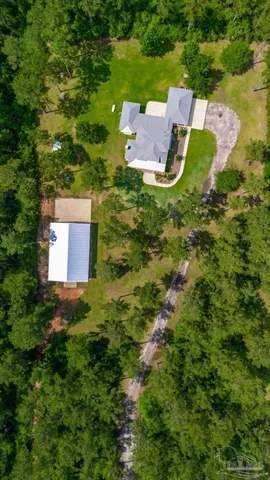 an aerial view of residential house with outdoor space and trees all around