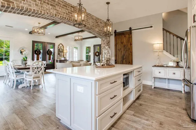 a large white kitchen with kitchen island a stove a sink a dining table and chairs