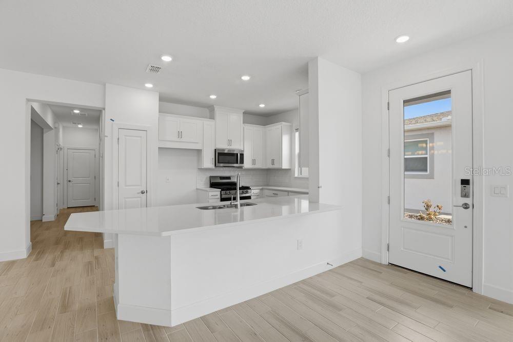 5375 Spoonflower Court St. Cloud, FL 34771 - Photo 2 of 42 a large kitchen with stainless steel appliances kitchen island a large counter top and a wooden floors