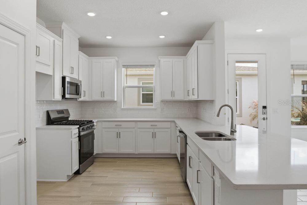 5375 Spoonflower Court St. Cloud, FL 34771 - Photo 6 of 42 a kitchen with stainless steel appliances granite countertop white cabinets a sink dishwasher and a stove top oven with wooden floor