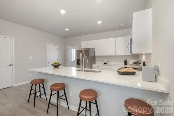 a kitchen with stainless steel appliances a table chairs and a refrigerator