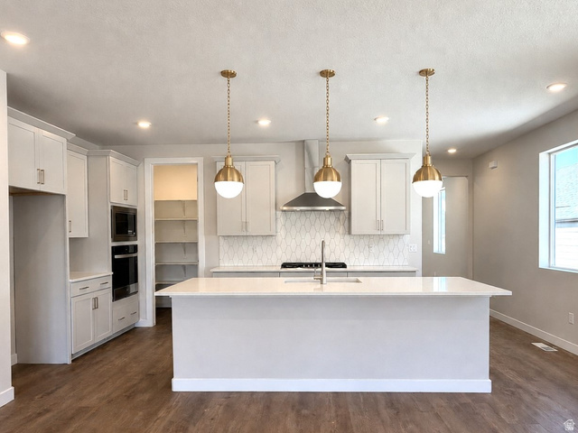 539 East Rimrock Lane Heber City, UT 84032 - Photo 2 of 13 Modern kitchen featuring a large central island with a light-toned countertop, complemented by three brass pendant lights and recessed lighting. This image has been digitally staged or enhanced via artificial intelligence. These photos are for illustrativ
